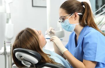 Hygienist checking woman's teeth